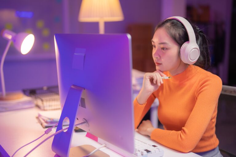 Young,Asian,Woman,Wearing,Headphones,Working,From,Home,At,Night,